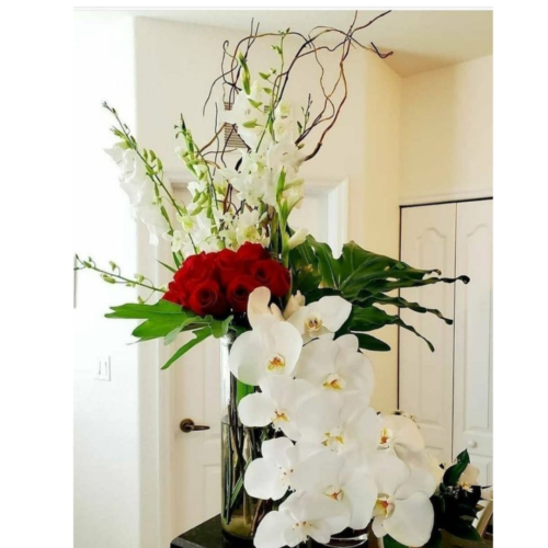 beautiful orchid flower arrangement with a glass base with red roses