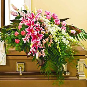 A blushing pink and white Casket Spray is designed with Dendrobium Orchids, Pink Lillies, Carnation, Pink Roses, Alstroemerias and Foliage