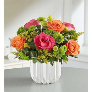 A fresh arrangement of hot-pink, orange & yellow blooms, assorted greenery and looped Ti leaves for a contemporary flair