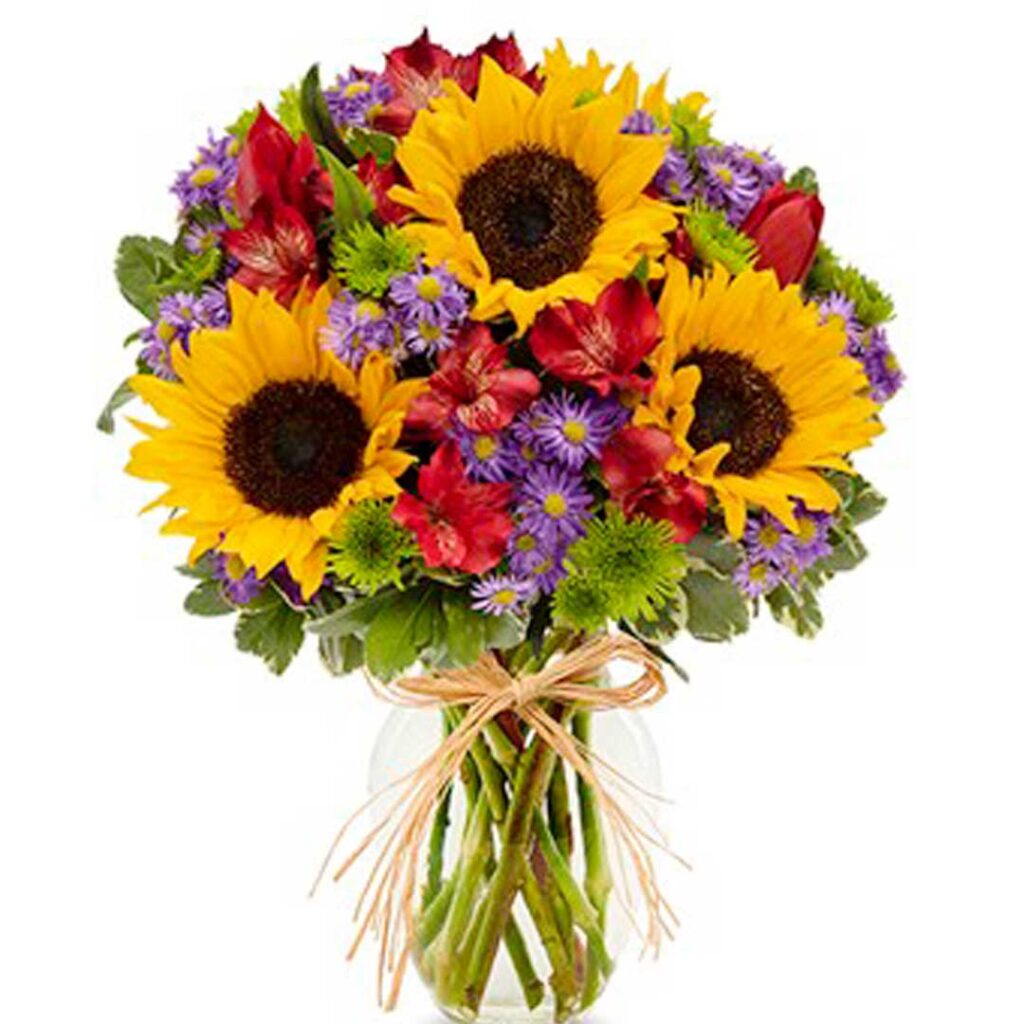 This bright assortment of alstroemeria, button poms, Monte casino, sunflowers and tulips in an elegant clear glass vase.